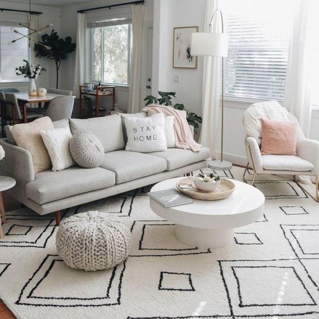 Phòng khách sáng sủa với ghế sofa và gối màu trắng không chỉ là một trung tâm mà còn là một vách ngăn giữa phòng khách và nhà bếp.