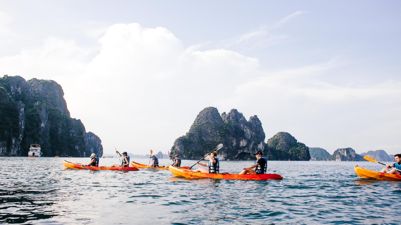 Adventure Vietnam Travel kayaking in Ha Long Bay surrounded by towering limestone cliffs and emerald waters