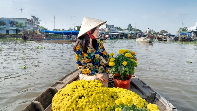 Tourists enjoying a river cruise lined with coconut palms on a Ho Chi Minh to Mekong Delta tour
