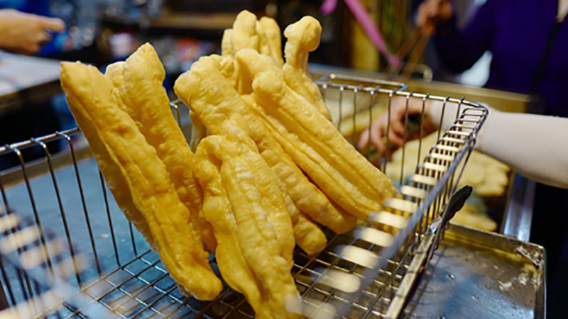 Hanoi Street Food Tour: A Flavorful Journey Through the Capital’s Best Local Eats 6 Vendor frying Hanoi bagel twists at a street stall