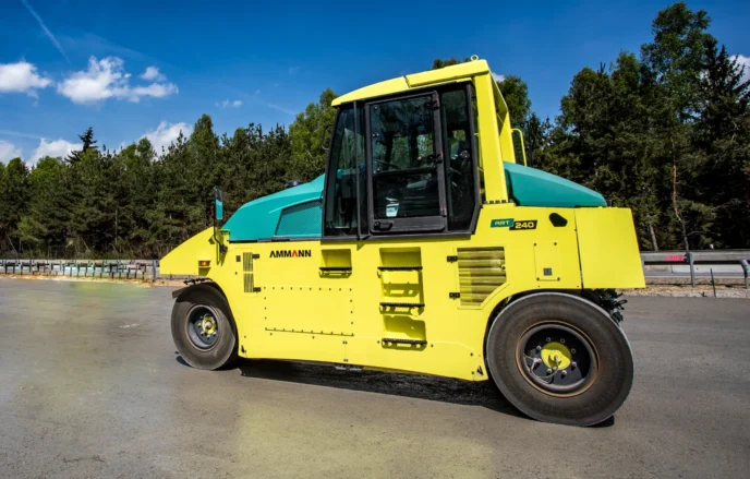 Hình ảnh xe lu bánh hơi AMMANN AP240 được chụp tại công trường thi công, thể hiện rõ thiết kế mạnh mẽ và hiệu suất vượt trội của thiết bị. Với màu vàng đặc trưng, xe lu nổi bật giữa nền đất cứng, cho thấy khả năng làm việc hiệu quả trên nhiều loại địa hình.