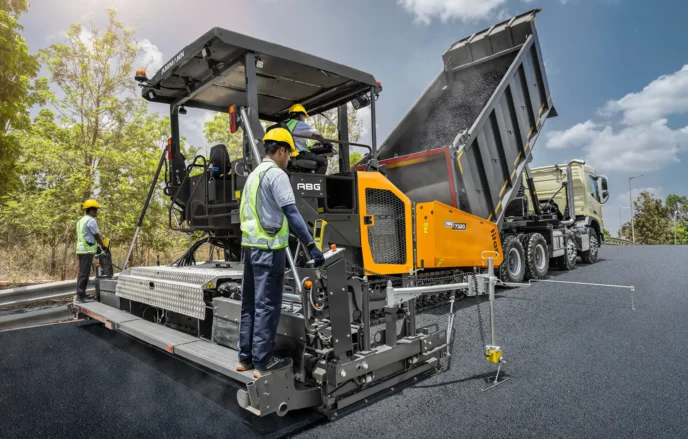 Hình ảnh máy rải thảm AMMANN ABG 7820 tại kho Multico thể hiện rõ nét một thiết bị công trình cỡ lớn, với ngoại hình mạnh mẽ, cấu trúc bánh xích vững chãi, sẵn sàng vận hành trên mọi địa hình. 
